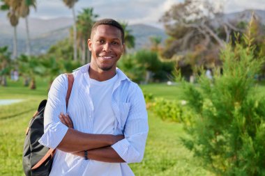 Kollarını kavuşturmuş Afro-Amerikan bir adamın açık hava portresi. Kameraya bakıyor, uzayı kopyalıyor.