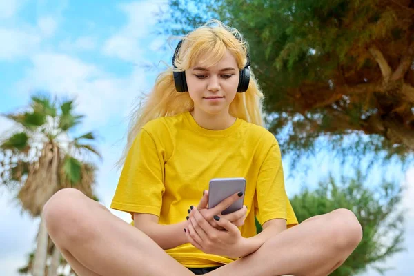 Krásná žena teenager ve sluchátkách s smartphone venkovní. — Stock fotografie