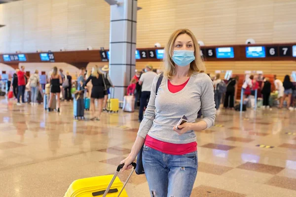 Mujer pasajera con máscara de protección médica en el aeropuerto con maleta de equipaje —  Fotos de Stock