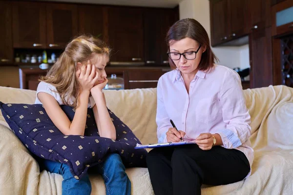 Sosyal hizmetler görevlisi bebek kızla konuşuyor, evdeki kanepede toplantı yapıyor.