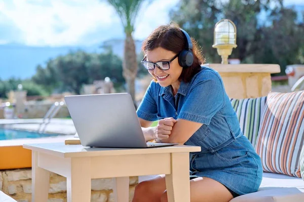 Donna d'affari di mezza età in cuffia utilizzando laptop all'aperto — Foto Stock