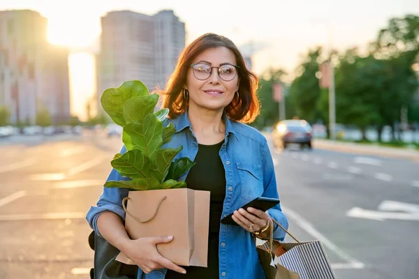 拿着购物袋的女人，买了植物在户外散步 — 图库照片