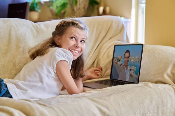 Ragazza bambino guardando flusso video sul computer portatile, sdraiato sul divano a casa — Foto Stock