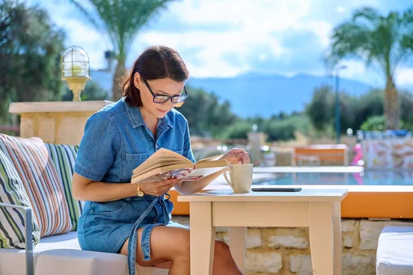 야외 수영장 독서 책 근처에서 쉬고 있는 중년 여성 — 스톡 사진