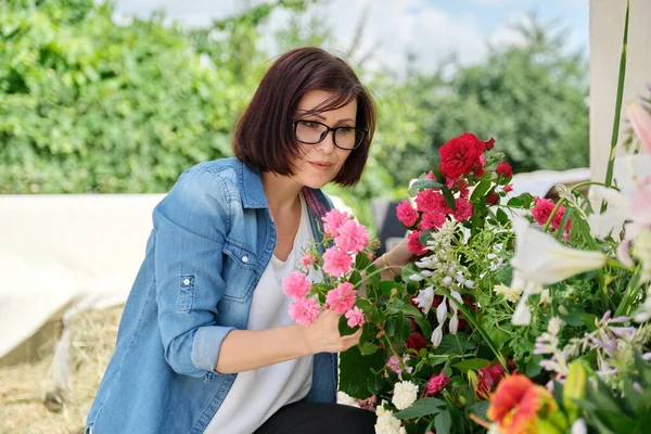 Vrouw bloemist maken bloemstuk in mand outdoor. — Stockfoto