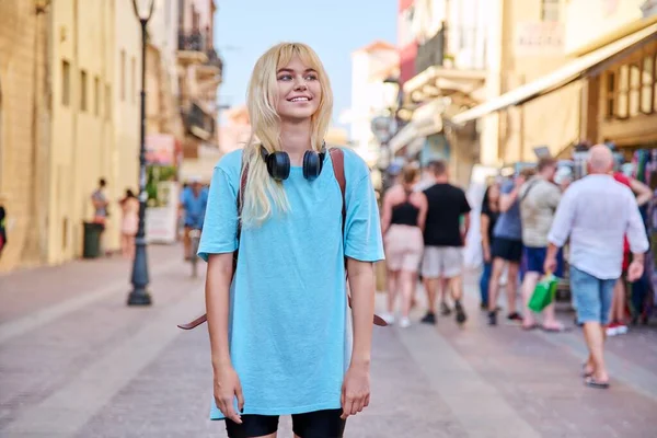 Молода жінка в навушниках з рюкзаком на вулиці туристичного міста — стокове фото