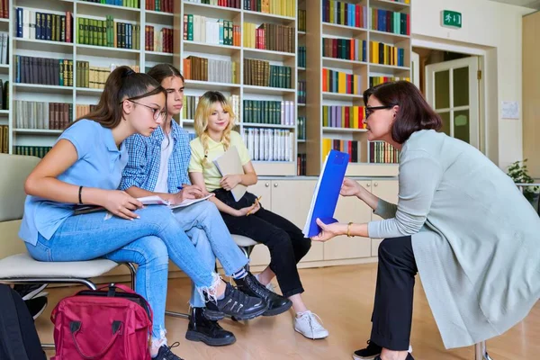 Groep tienerstudenten studeert in bibliotheekklas met vrouwelijke leraar mentor — Stockfoto