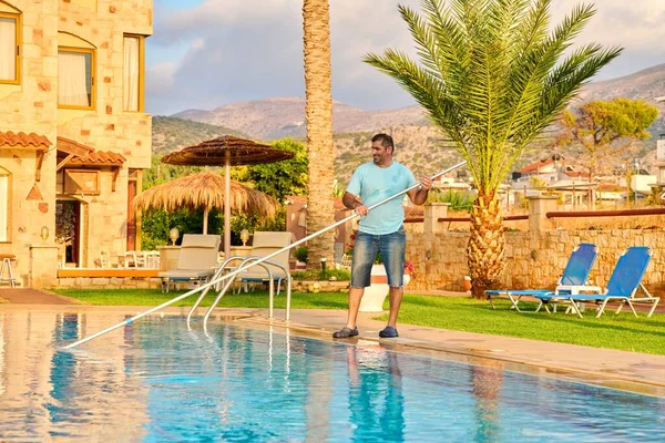 Man cleaning outdoor swimming pool, beautiful scenic view of nature background — Zdjęcie stockowe