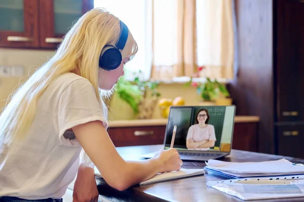 十代の女性学生でヘッドフォンで自宅でラップトップを使用して教師と話をする — ストック写真