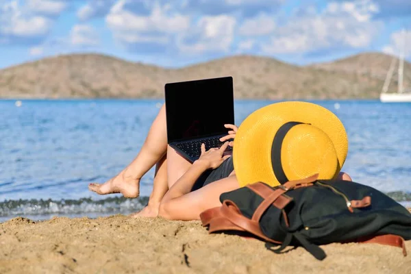 Mujer madura tomando el sol en la playa con un ordenador portátil — Foto de Stock