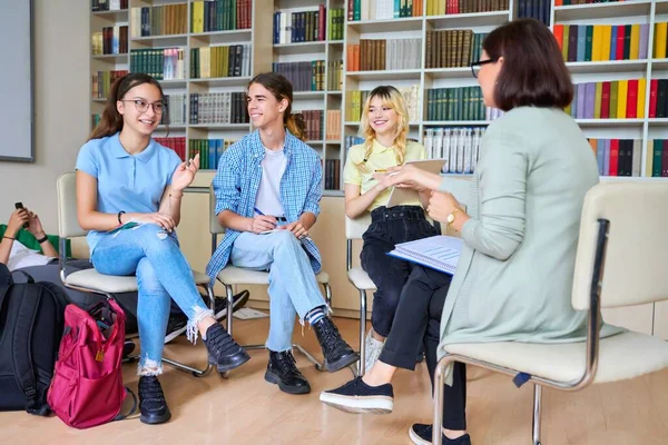 Groep tienerstudenten studeert in bibliotheekklas met vrouwelijke leraar mentor — Stockfoto