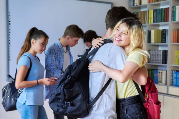 Amigos adolescentes los estudiantes se abrazan cuando se encuentran en la biblioteca —  Fotos de Stock