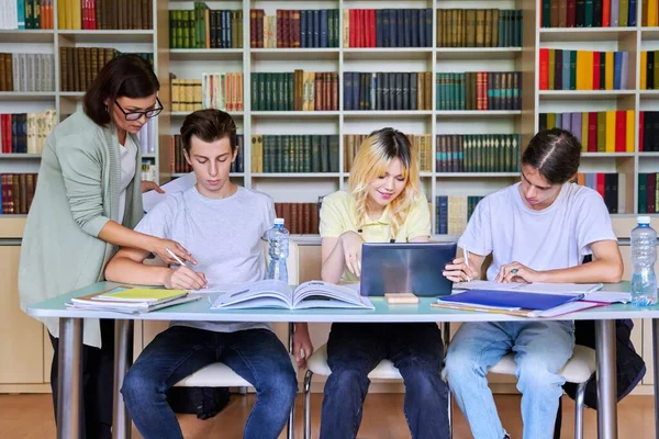 Grupo de estudantes adolescentes estudando em aula de biblioteca com professora mentora — Fotografia de Stock