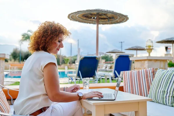 Orta yaşlı iş kadını dışarıda dizüstü bilgisayar kullanıyor..