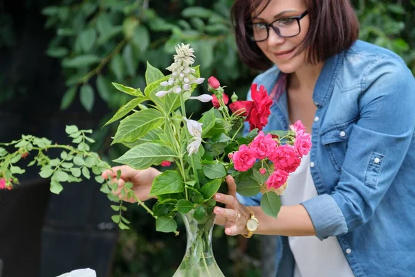 Женщина делает букет цветов в вазе под открытым небом — стоковое фото
