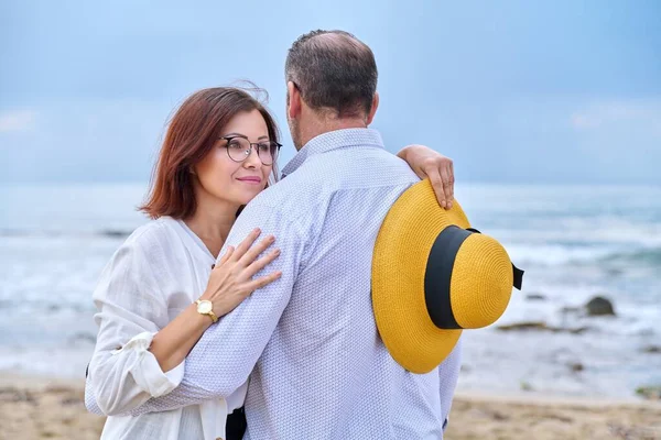 Portret van gelukkig knuffelen middelbare leeftijd paar, zee natuur hemel golven achtergrond. — Stockfoto