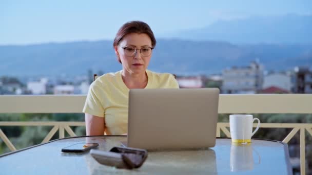 Donna di mezza età che lavora in un ufficio domestico su una terrazza. — Video Stock