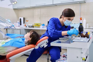 Doktor dişçi genç bir bayan hastayla ilgileniyor.