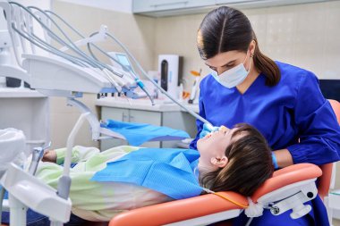 Doktor dişçi genç bir bayan hastayla ilgileniyor.