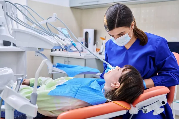 Doktor dişçi genç bir bayan hastayla ilgileniyor.