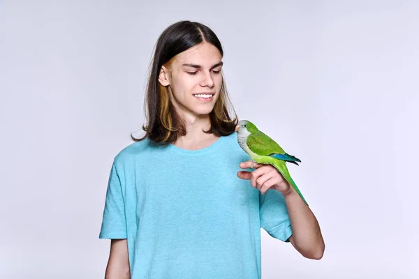 Young male with domestic green Quaker parrot on light studio background —  Fotos de Stock