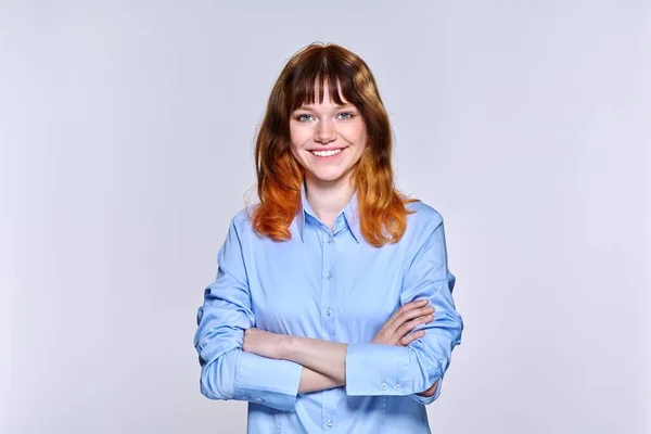 Portrait of young red-haired female looking at camera on light studio background — 스톡 사진