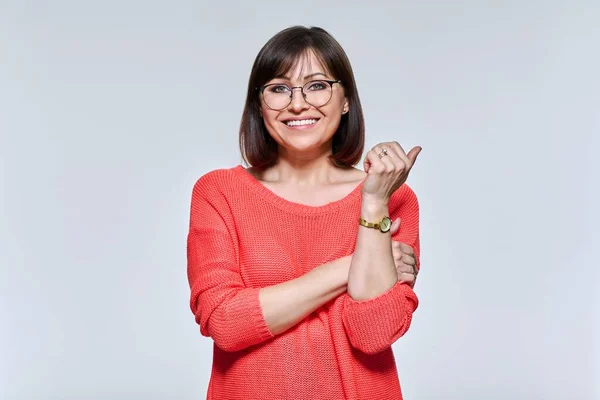 Portrait of middle aged woman looking at camera, on light studio background — Stockfoto