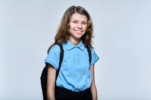 Portrait of schoolgirl 11, 12 years old with backpack, girl looking at camera on light studio background — 스톡 사진