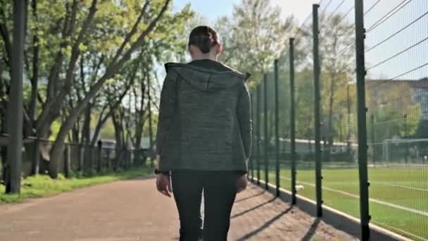 Vista trasera de la mujer en ropa deportiva caminando a través de un estadio al aire libre — Vídeos de Stock