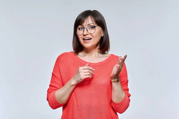 Portrait of a mature woman talking, looking at camera, on light studio background — Stock Photo, Image