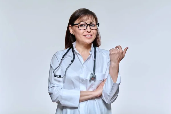 Portrait of female doctor looking at camera talking gesturing on light studio background — Stock fotografie