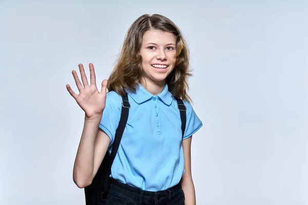 Portrait of schoolgirl with backpack, looking at camera waving hello or goodbye — 스톡 사진