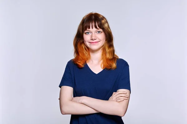 Açık renk stüdyo arka planında kameraya bakan kızıl saçlı genç bir kadının portresi. — Stok fotoğraf