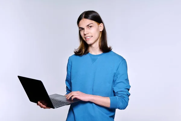 Teenage männlich student using laptop posing looking at camera on light studio background — Stockfoto