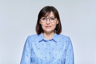 İş portresi. Olgun bir kadın. Işık stüdyosunun arka planında kameraya bakıyor.
