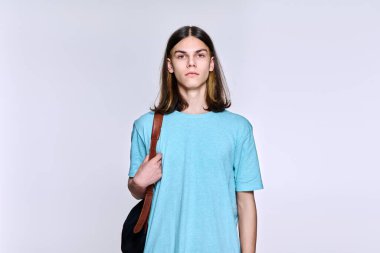 Sırt çantalı ciddi öğrenci portresi. Kameraya bakıyor. Hafif stüdyo geçmişi var.