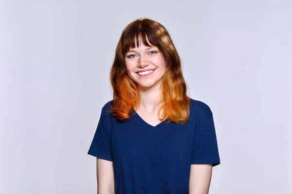 Portrait of young red-haired female looking at camera on light studio background — Stock Photo, Image