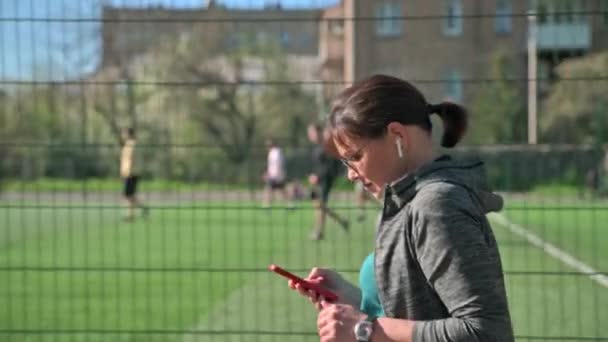 Ενεργή ώριμη γυναίκα σε αθλητικά ρούχα με smartphone, εξωτερική, προβολή προφίλ — Αρχείο Βίντεο