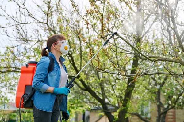 Woman with backpack garden spray gun under pressure handling peach tree —  Fotos de Stock