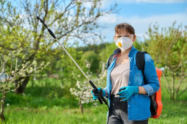 Woman with goggles and respirator with backpack garden spray gun under pressure — Foto de Stock