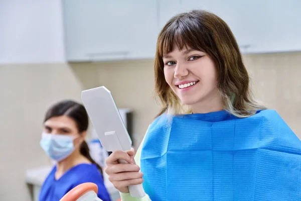 Tiener vrouw op zoek naar gezonde tanden in de spiegel, in tandartspraktijk — Stockfoto