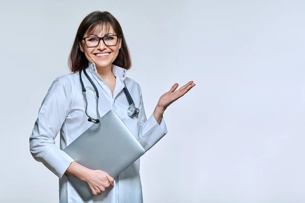 Retrato de médico feminino com laptop, no fundo do estúdio de luz — Fotografia de Stock