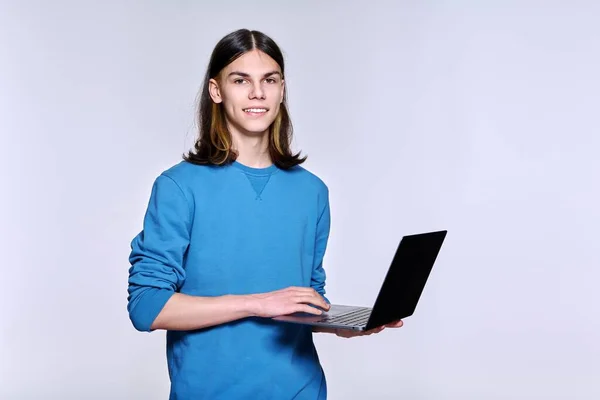 Teenage männlich student using laptop posing looking at camera on light studio background — Stockfoto