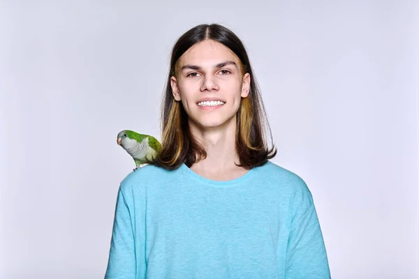 Young male with domestic green Quaker parrot on light studio background — Stock Fotó