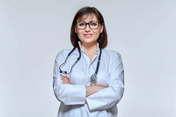 Portrait of female doctor looking at camera on light studio background — Fotografia de Stock