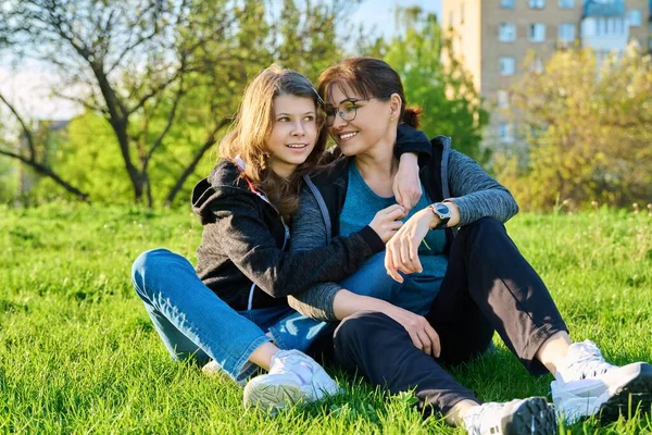 Happy mother and daughter hugging sitting on grass — Stock Photo, Image