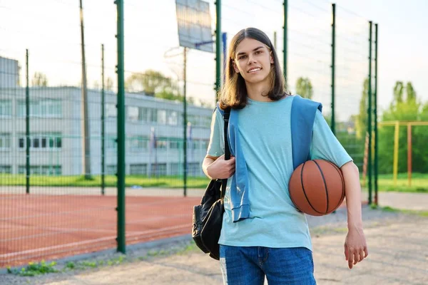 Portrait of student guy with backpack ball, near outdoor basketball playground — Stock Photo, Image