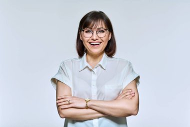 Portrait of positive confident middle aged woman looking at camera, on light background