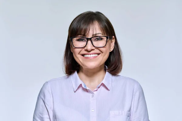 Portrait of middle aged woman looking at camera, on light studio background — Stok fotoğraf