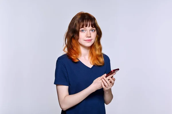 Serious sad teenage female with smartphone, looking at camera — Stock Photo, Image